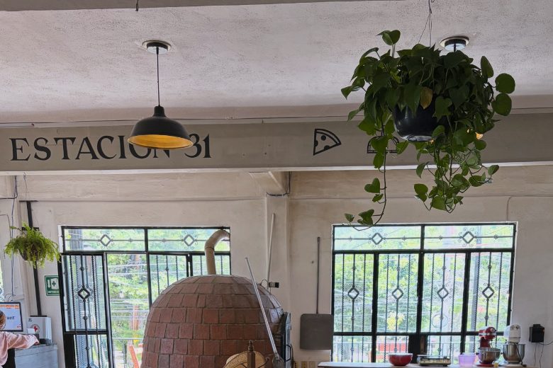 Interior de Estación 31 en Peña de Bernal: letrero pintado y horno de ladrillo frente a los ventanales