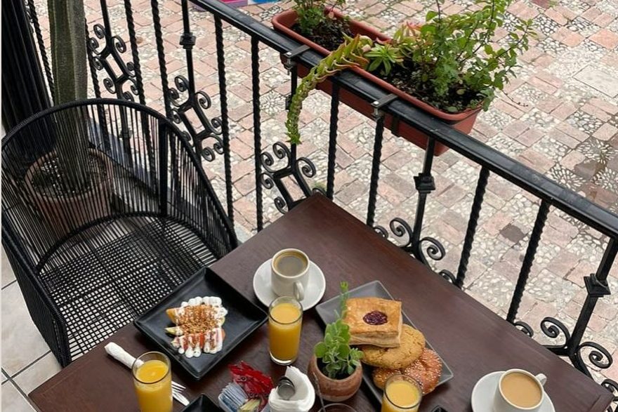 Mesa de desayuno en el balcón de Estación 31 Tequisquiapan, con las letras de Tequis en el Parque La Pila